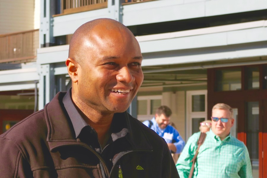 Emmanuel full of smile on his face with two men in the background.